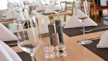 Une table à manger dressée avec des verres à vin, des salières et des poivrières, et une serviette.
