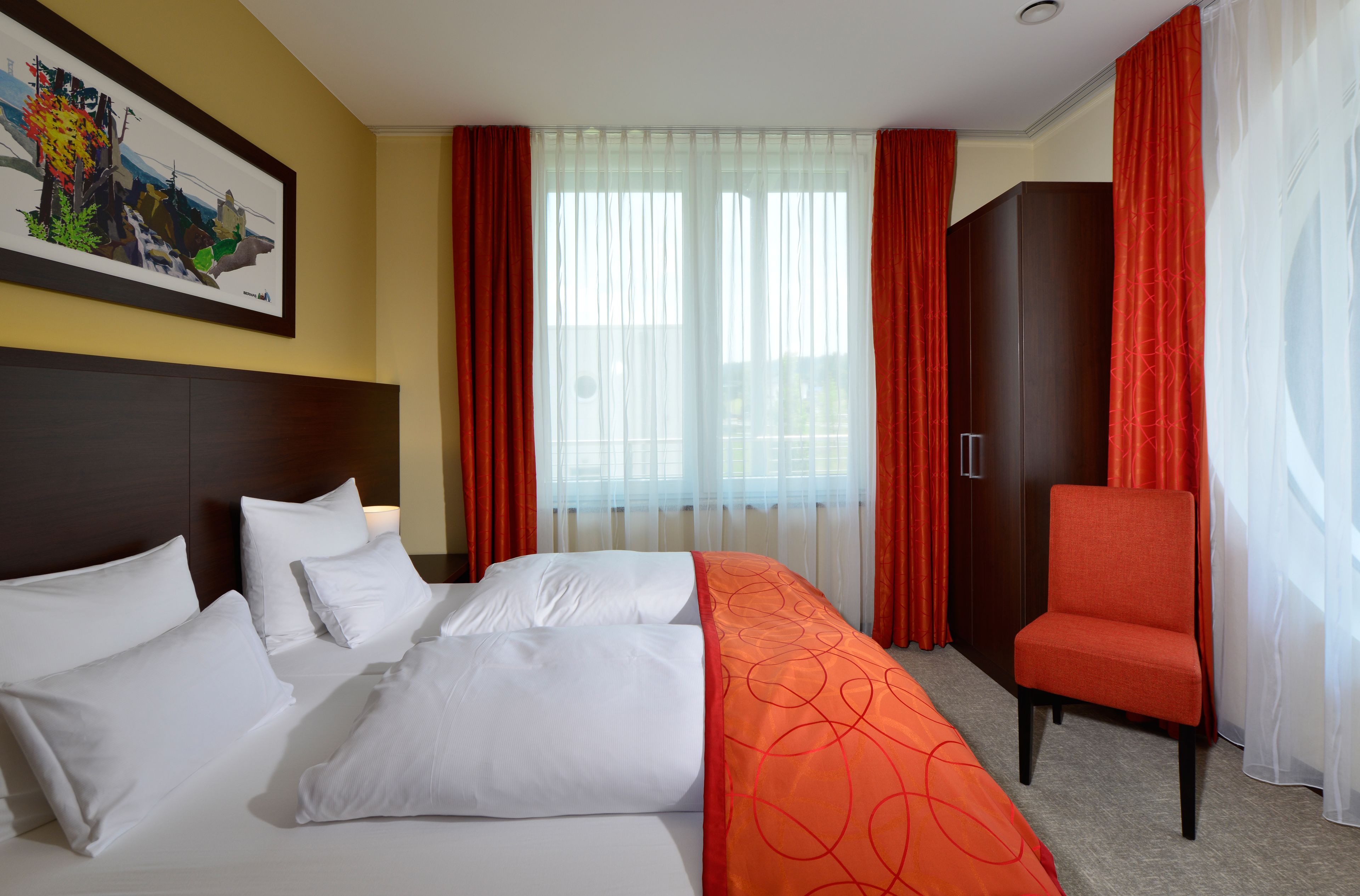 A hotel room with a bed, a chair, and a wardrobe.