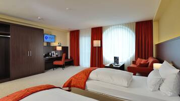 Habitación de hotel con dos camas, un escritorio, una silla, un televisor y vistas al exterior.