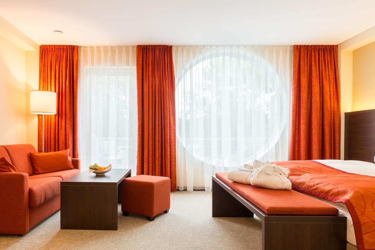 Une chambre d’hôtel avec un lit, un canapé, une petite table et un banc.