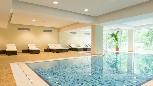 A swimming pool with lounge chairs and a potted plant. - ARIBO Hotel Erbendorf (Erbendorf)