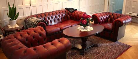 A living room with a red leather sofa set, a wooden coffee table, and a patterned rug.