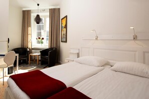 A hotel room with a bed, a desk, a chair, and a window with curtains. - Hotel Emma (Östersund)
