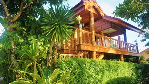 A wooden structure with a balcony, surrounded by lush greenery. - Ruenthai Boutique (Sa Khu)