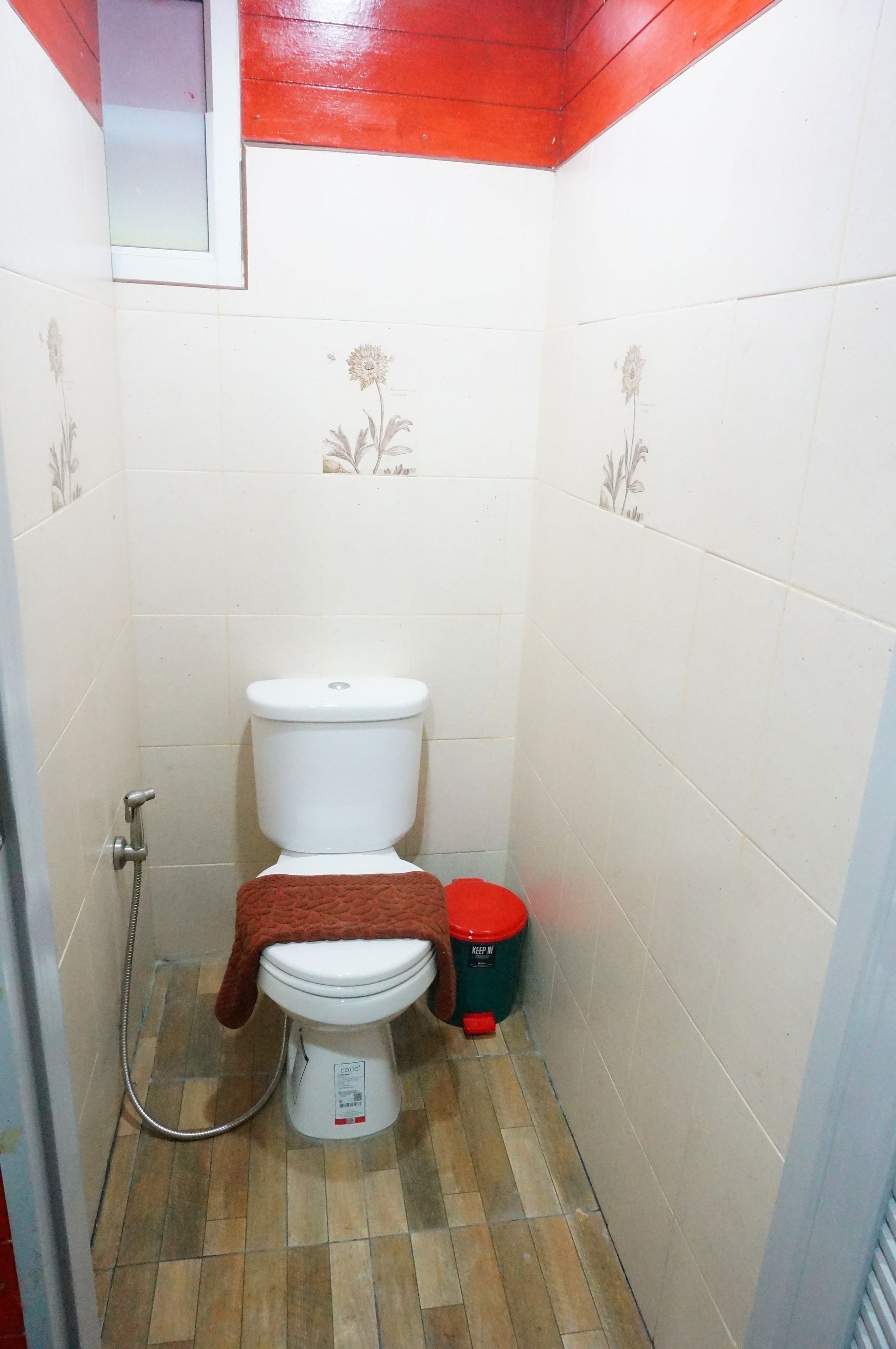 A small bathroom with a toilet, a shower, and a trash bin.