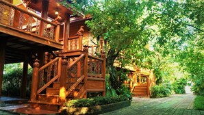 A traditional wooden building with a covered staircase and a garden pathway. - Ruenthai Boutique (Sa Khu)