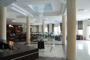 A spacious lobby with a reception desk, seating area, and a bar.