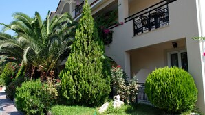 A multi-story building with balconies, lush greenery, and a well-maintained garden. - Letsos Hotel (Zakynthos)