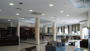 A spacious lobby with a reception desk, seating areas, and a bar. - Letsos Hotel (Zakynthos)