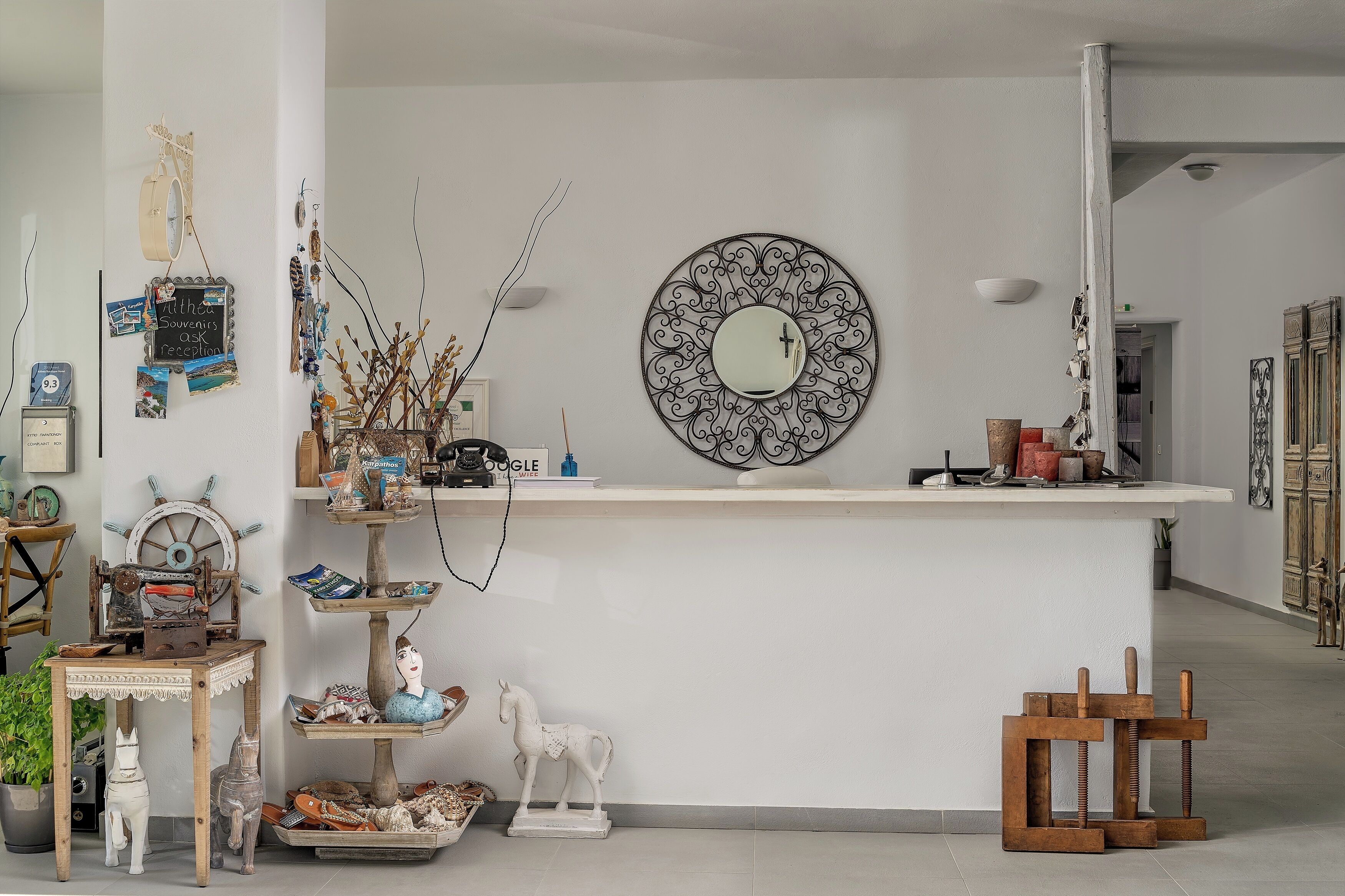 A reception area with a white counter, a round mirror, and various decorative items.
