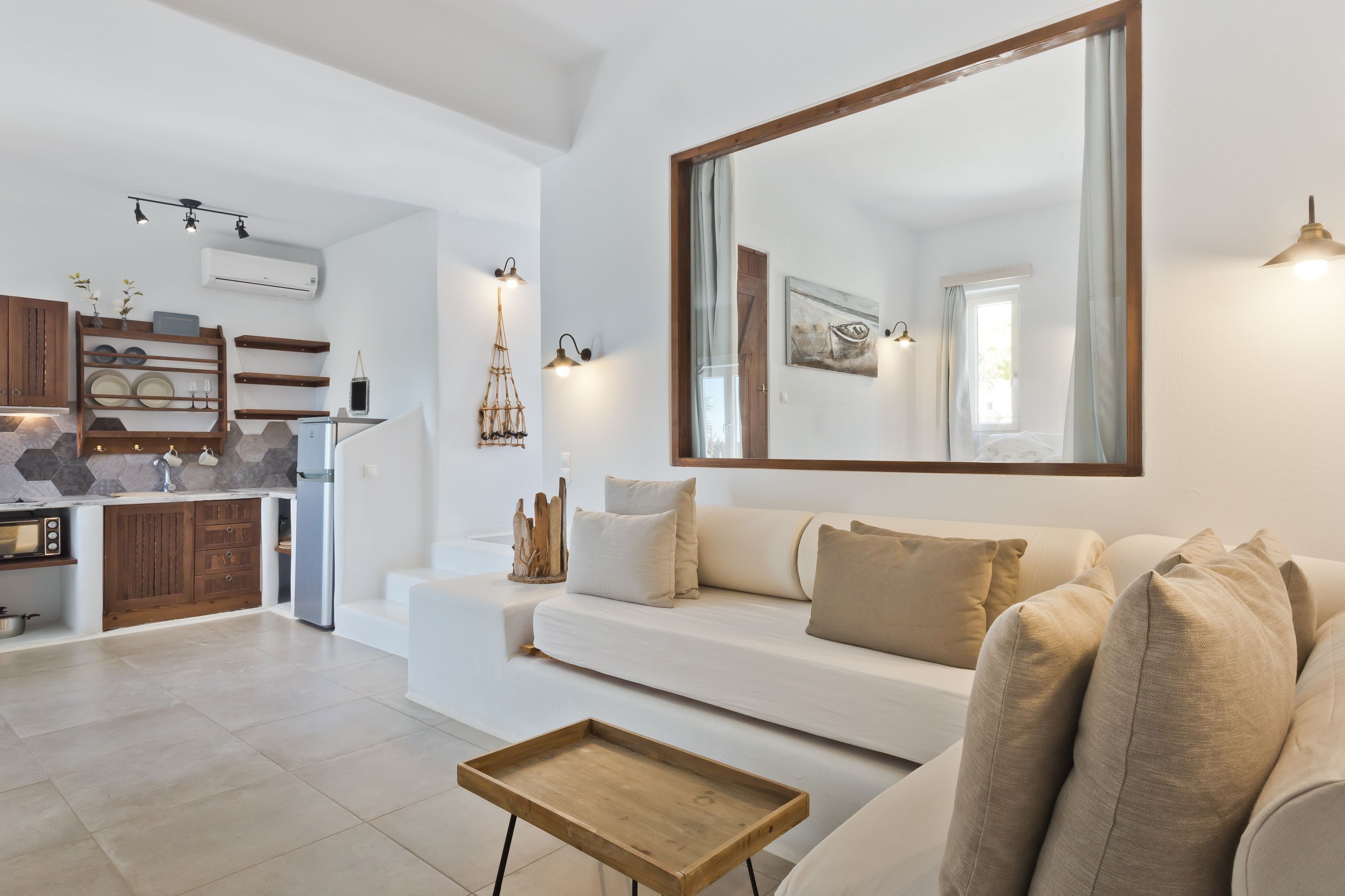 A modern living room with a white sofa, a wooden coffee table, and a large mirror.