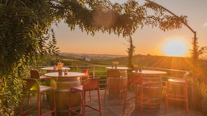 Un espace extérieur aménagé avec des tables et des chaises rondes, entouré de verdure et offrant une vue sur un paysage pittoresque.
