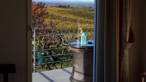 Une chambre avec vue sur un vignoble, accessible par une porte-fenêtre coulissante.