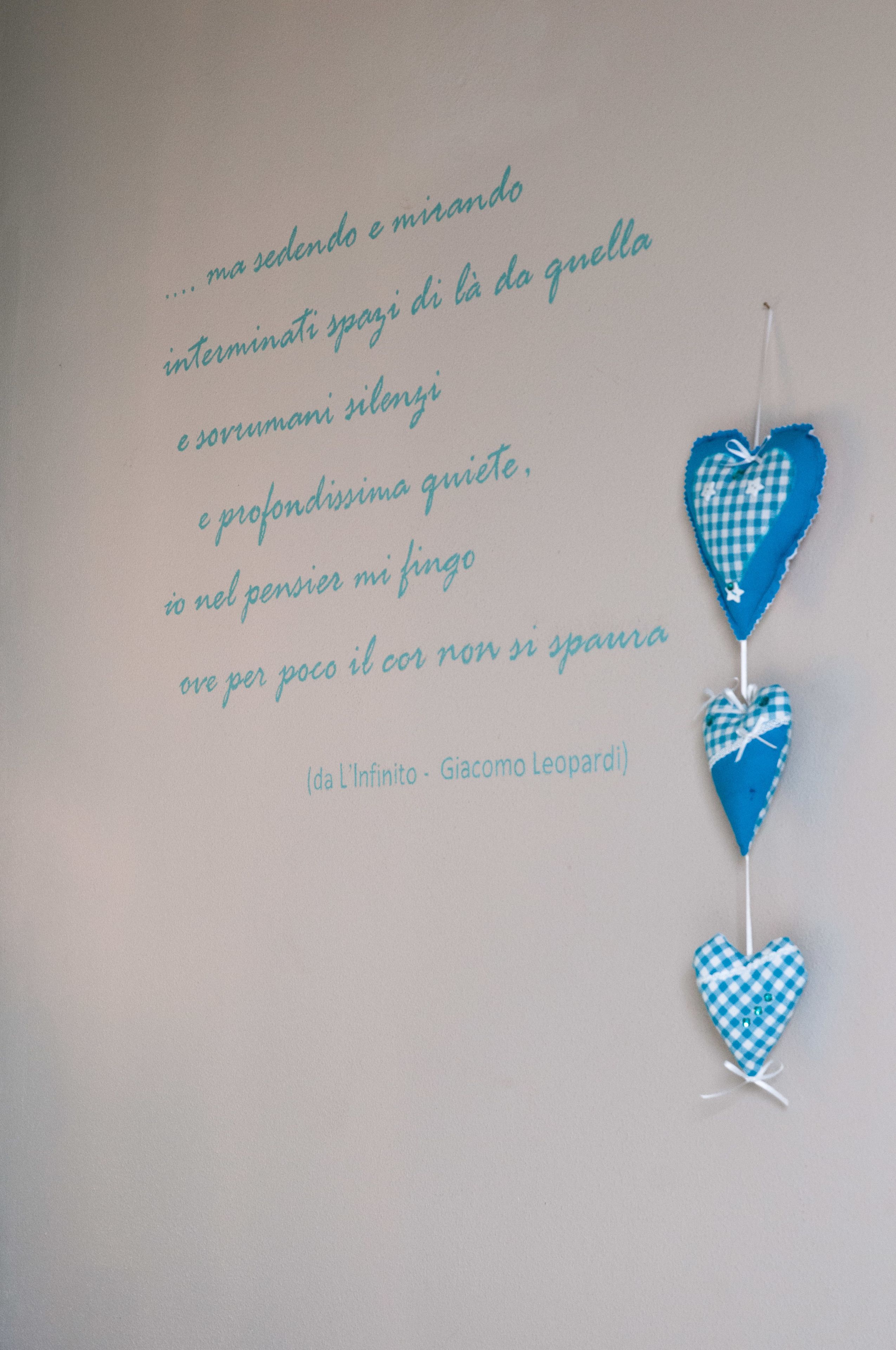 Un mur orné d’une citation en italien et de trois décorations en forme de cœur.