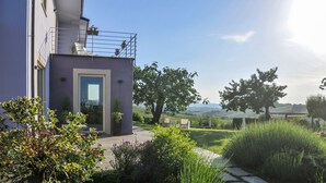 Un bâtiment moderne doté d’un balcon, d’un jardin avec différentes espèces de plantes et offrant une vue sur la campagne.