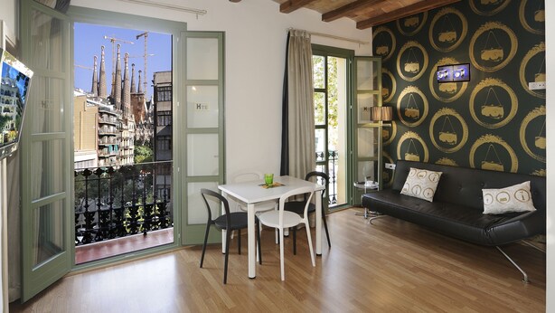 A room with a dining table, chairs, a sofa, and a TV. - Boutique Hostemplo Sagrada Familia (Barcelona)