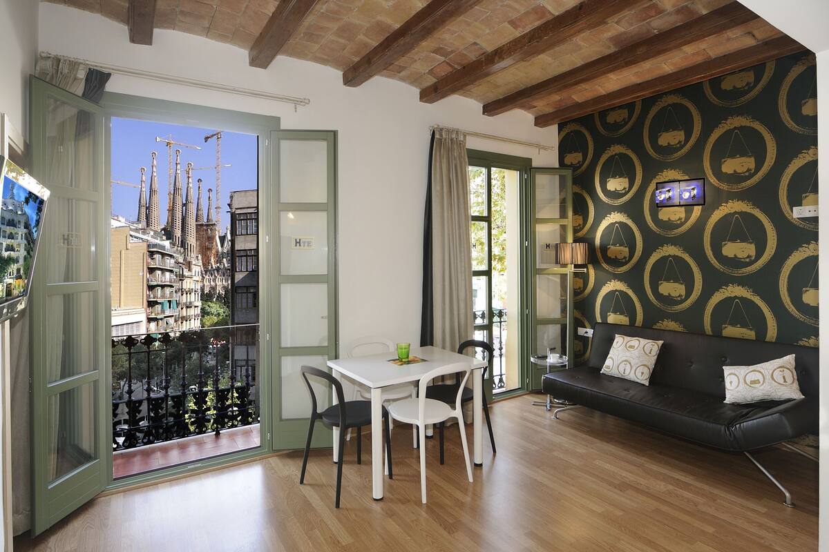 A room with a dining table, chairs, a sofa, and a TV.