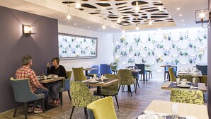 A modern dining area with multiple tables and chairs, featuring a patterned wall and ceiling design. - Boutique Hostemplo Sagrada Familia (Barcelona)