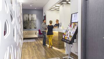 Un espace d’accueil au design moderne, comprenant un comptoir d’accueil, un grand tableau et un présentoir de cartes de bienvenue.