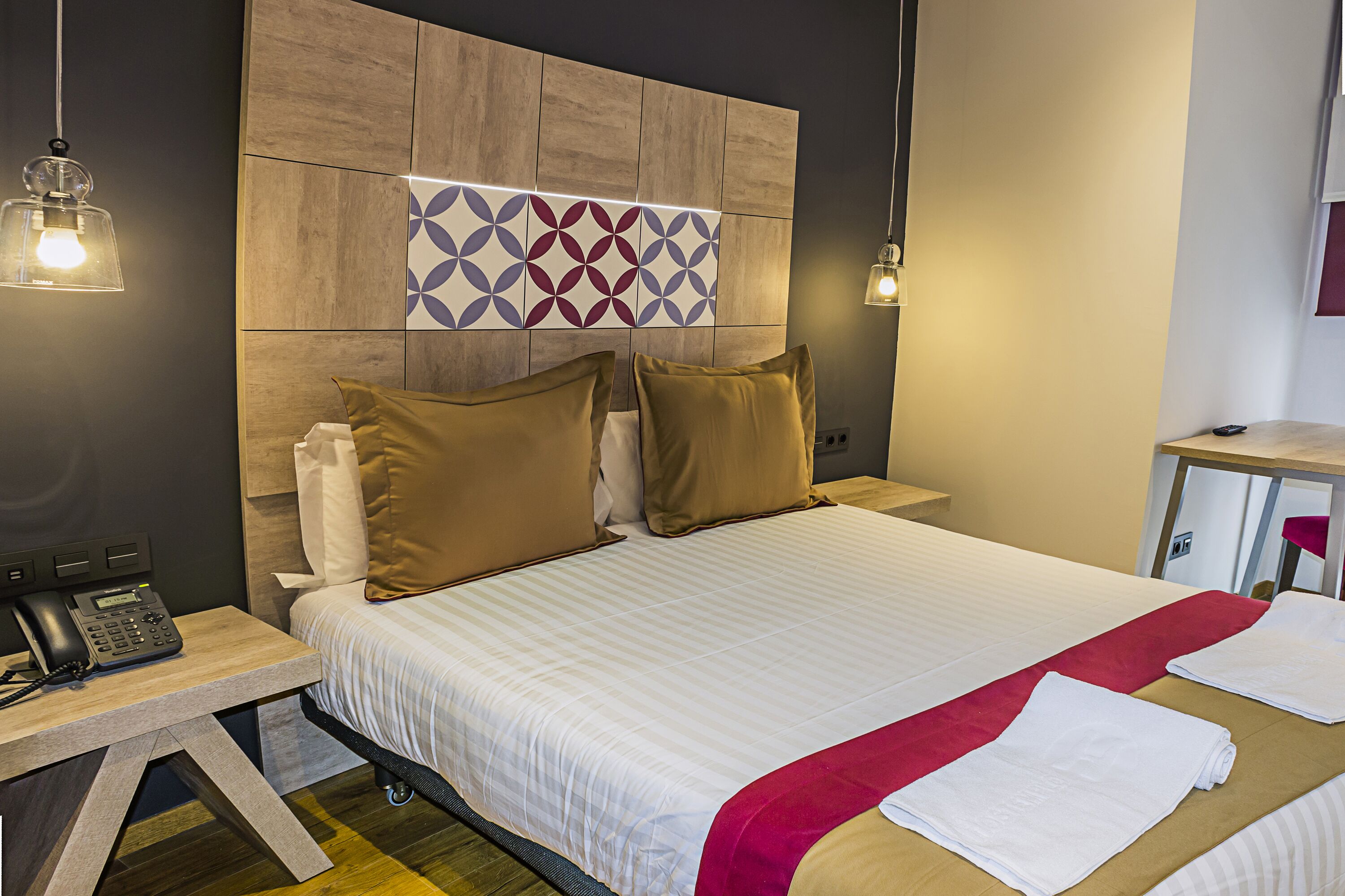Camera d'albergo con un letto grande, due comodini, un telefono e una lampada a parete.