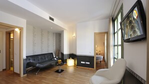 A modern living room with a leather sofa, a white armchair, and a glass coffee table. There is a fireplace with a decorative mirror above it. - Boutique Hostemplo Sagrada Familia (Barcelona)