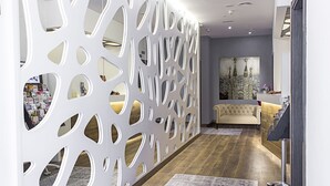 A modern hotel lobby with a decorative white partition, a reception desk, a sofa, and a large painting on the wall. - Boutique Hostemplo Sagrada Familia (Barcelona)