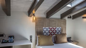 Ein Hotelzimmer mit einem Bett, einem Schreibtisch mit Telefon und Lampe sowie einer Wand mit geometrischem Muster.