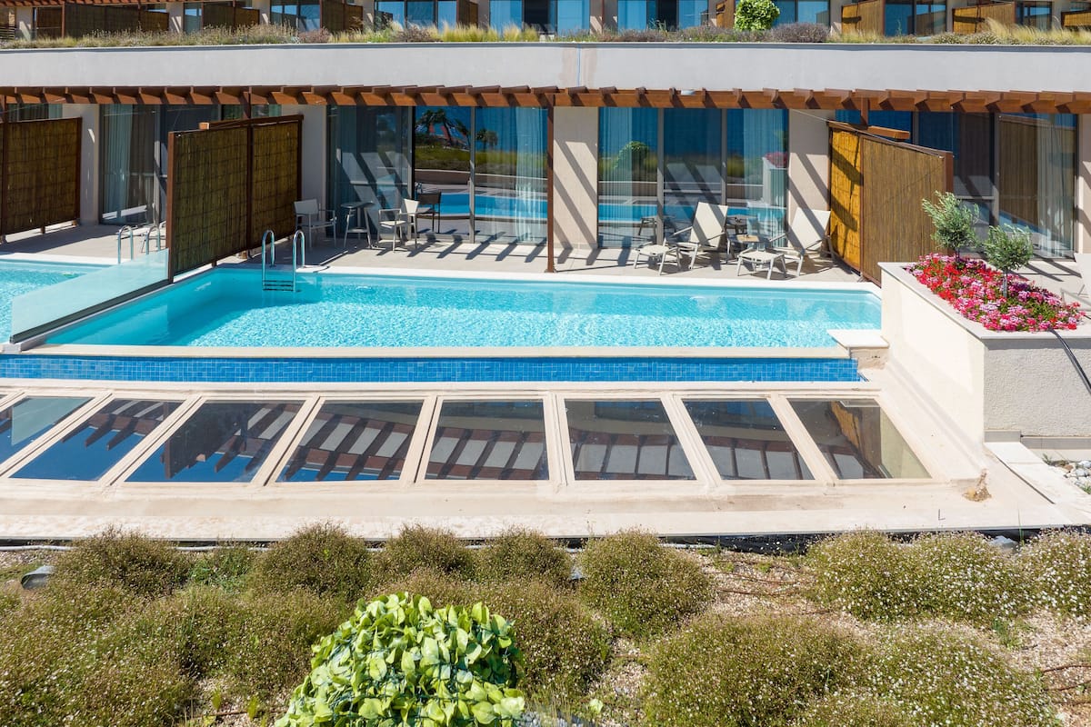 Ein modernes Hotel mit großem Außenpool, Liegestühlen und einer überdachten Sitzgelegenheit.