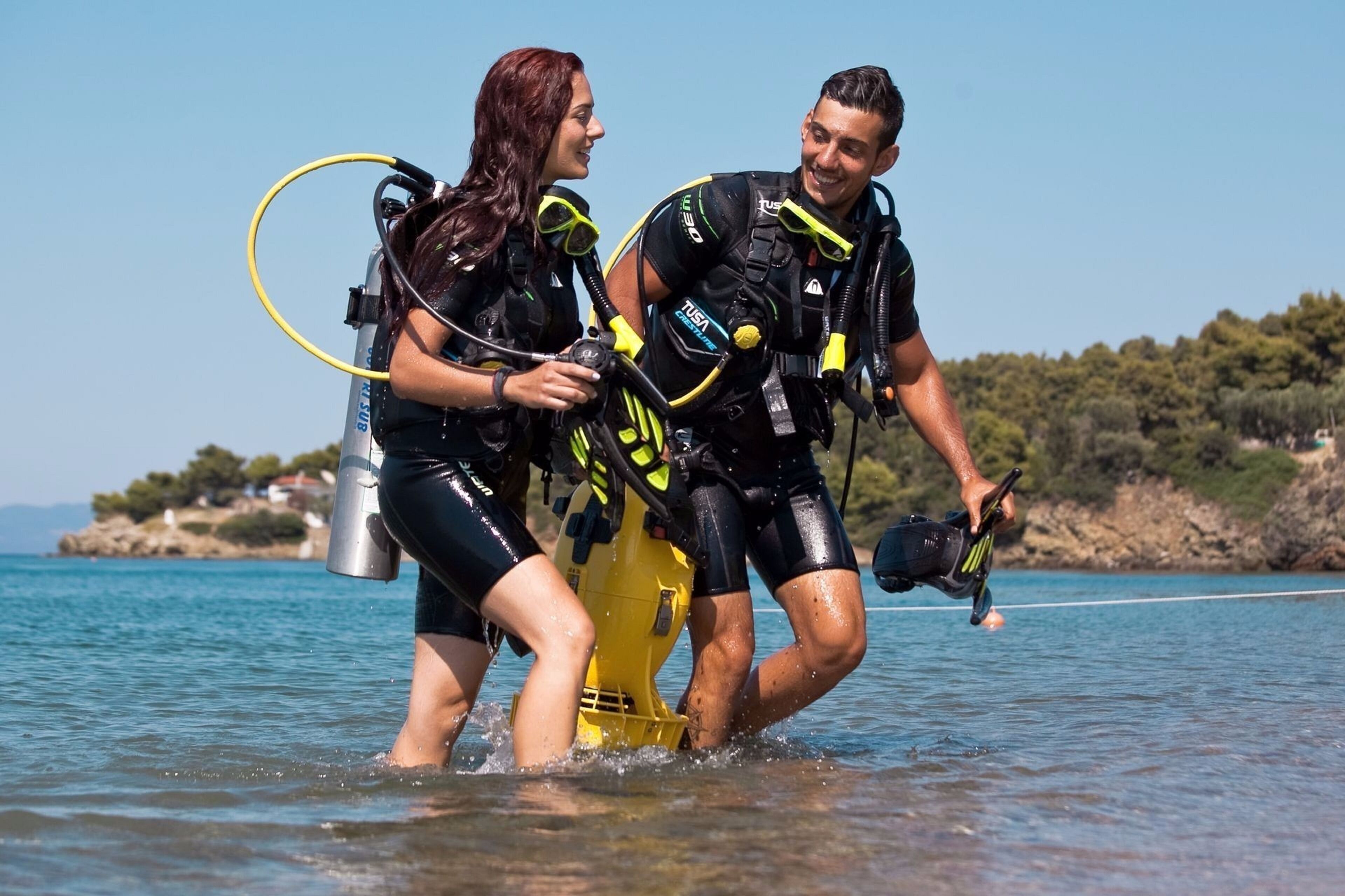 Zwei Personen in Tauchausrüstung machen sich bereit, ins Wasser zu steigen.