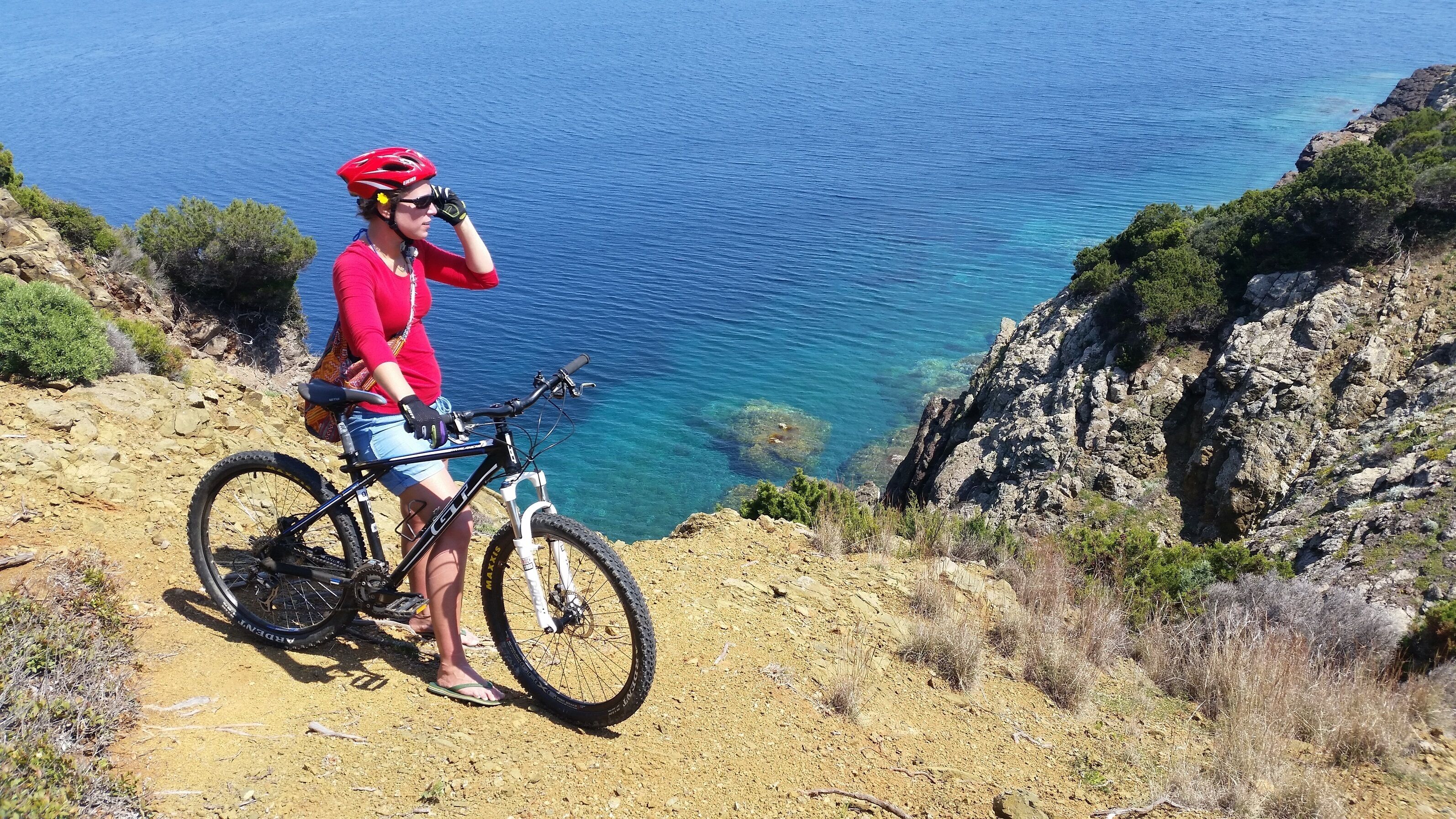 En person cykler på en mountainbike på en stenig sti med havudsigt.