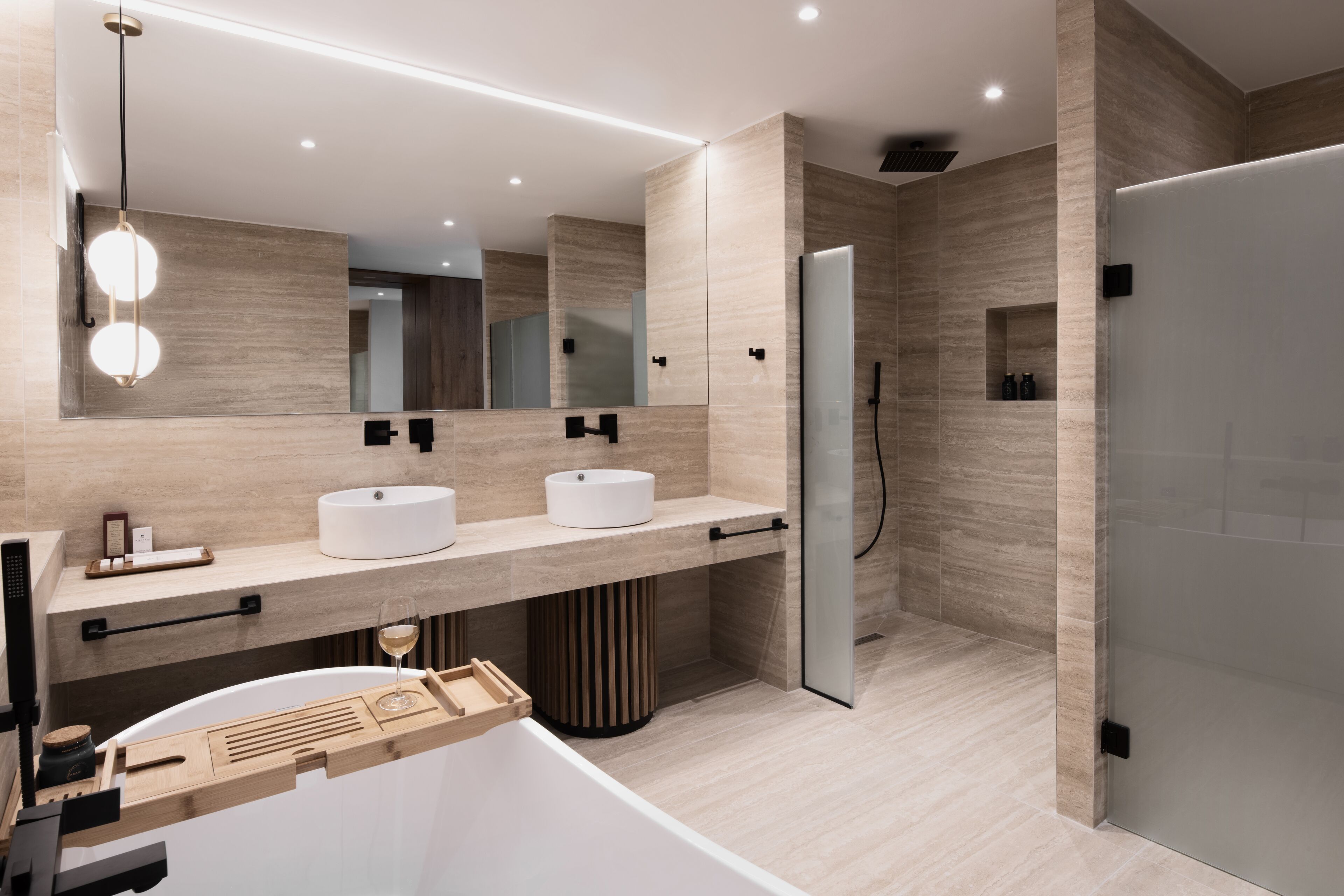 A modern bathroom with two sinks, a large mirror, and a shower area.