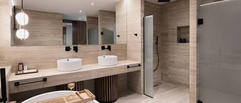 A modern bathroom with two sinks, a large mirror, and a shower area.