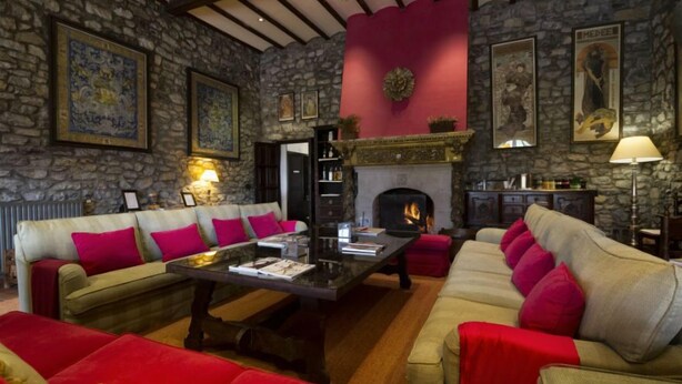 A cozy living room with stone walls, a fireplace, and comfortable seating. - Hotel Los Caspios (Colunga)