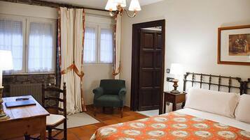 A bedroom with a bed, a chair, a desk, a lamp, and a door.