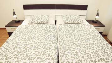 A double bed with a patterned bedspread, two bedside tables with lamps, and a dark headboard.