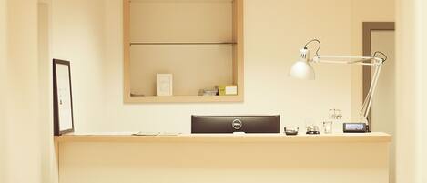 A clean, minimalist desk area with a Dell computer, a desk lamp, and a mirror above the desk.