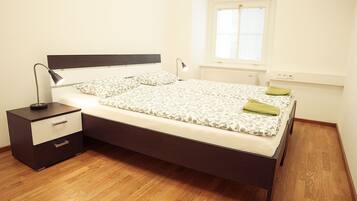 A bedroom with a bed, a nightstand, a lamp, and a window.