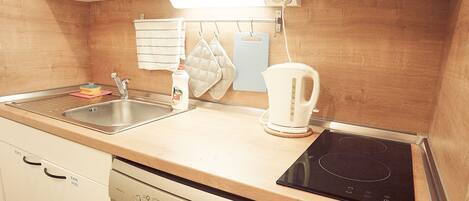A kitchen with a dishwasher, a kettle, and a stove.
