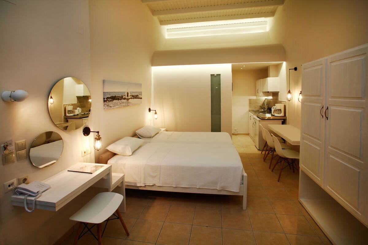 A hotel room with a bed, bedside table, chair, desk, and wardrobe.
