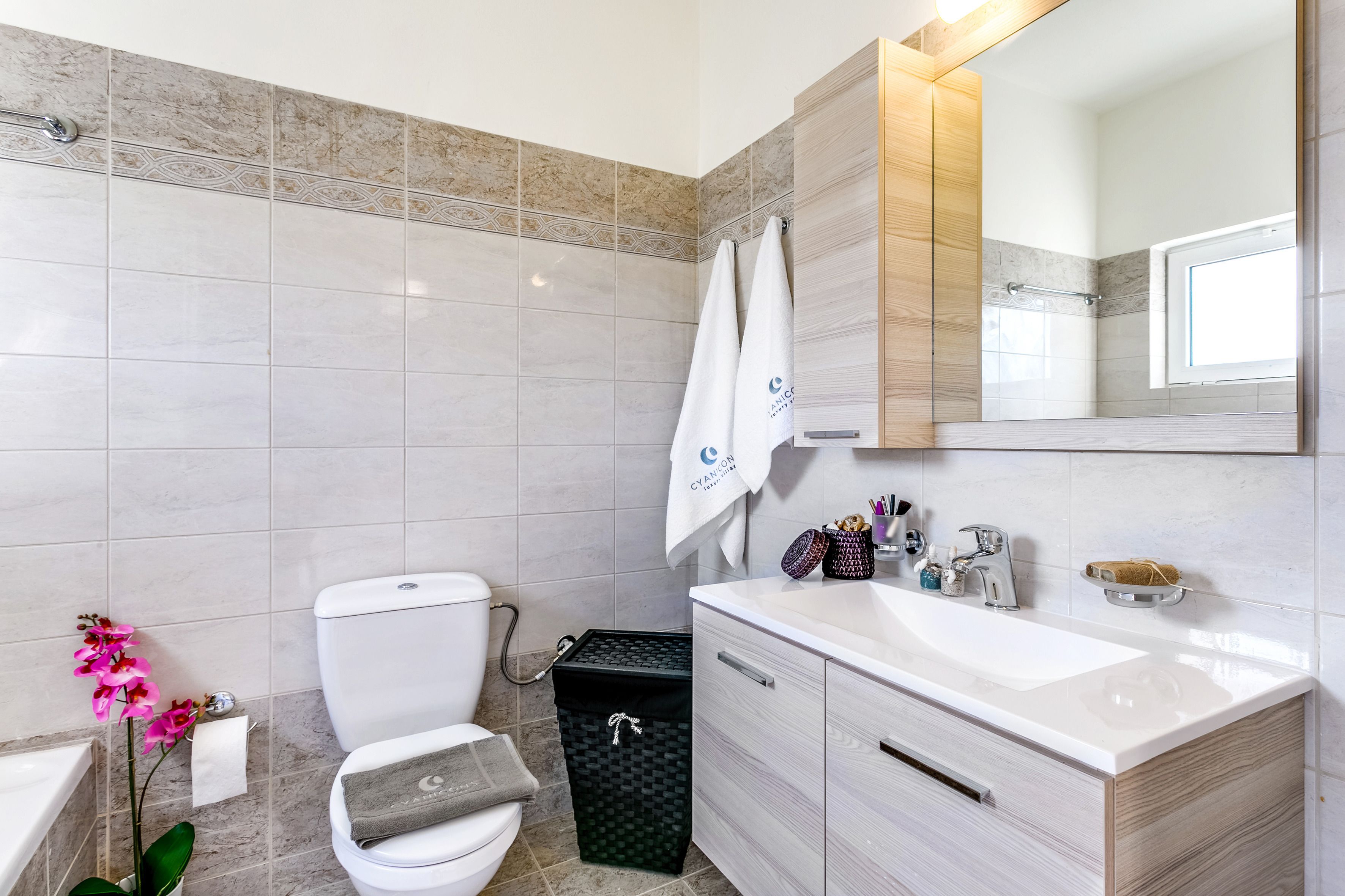Et moderne badeværelse med toilet, vask og spejl.