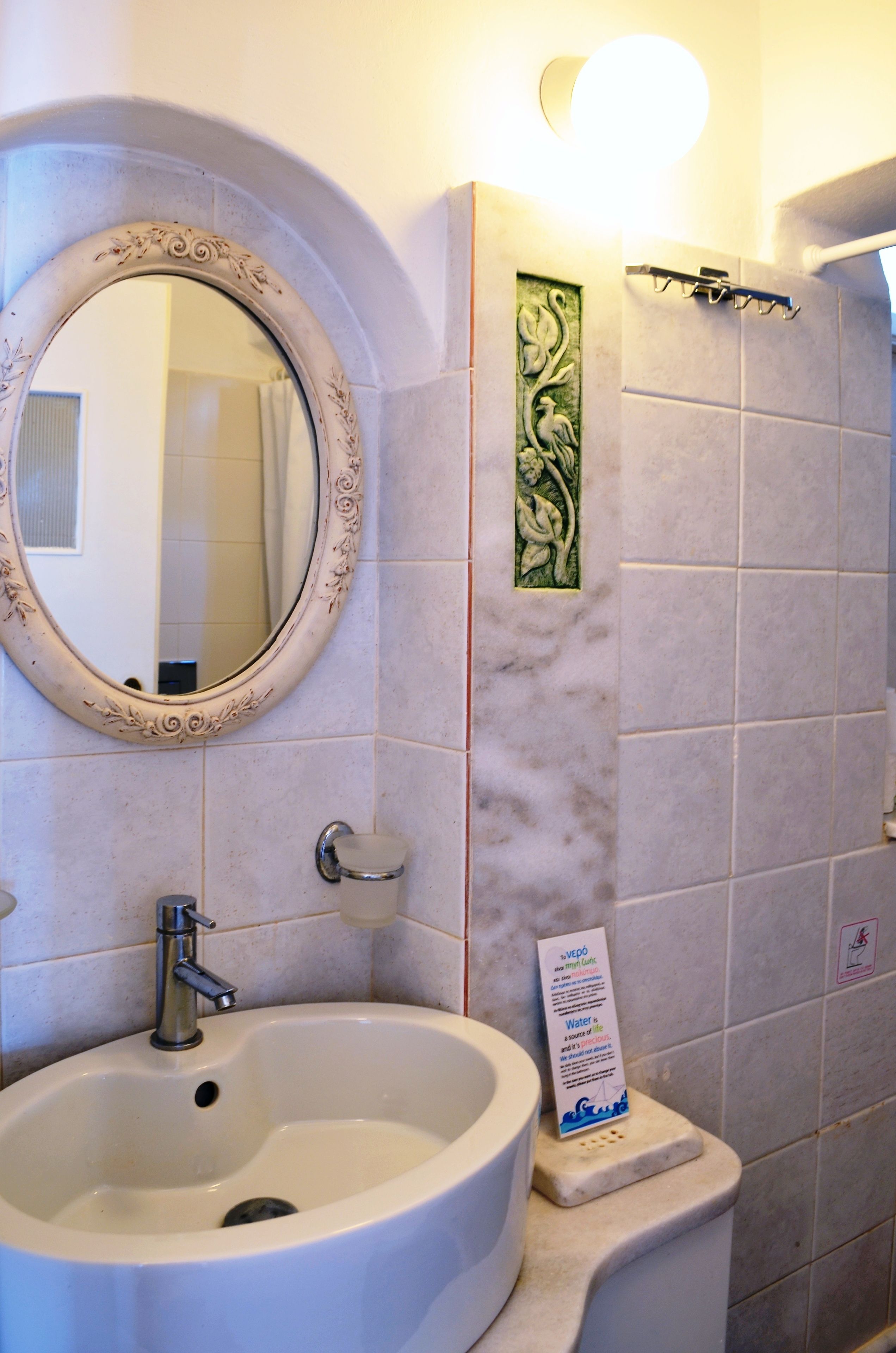 A bathroom with a round mirror, a sink, and a shower area.