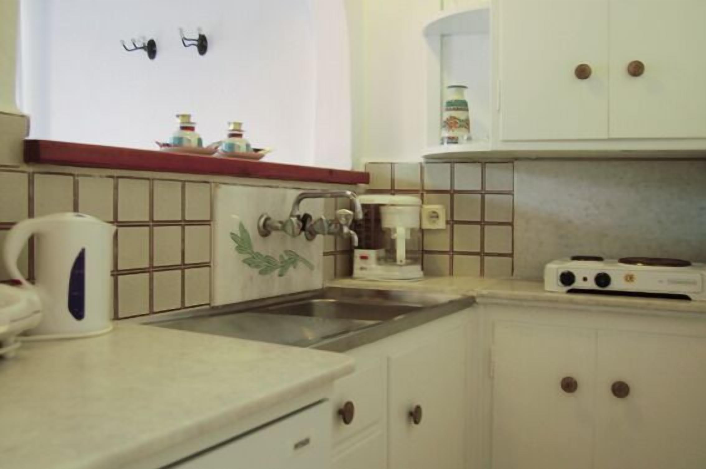 A kitchen with a sink, stove, and cabinets.