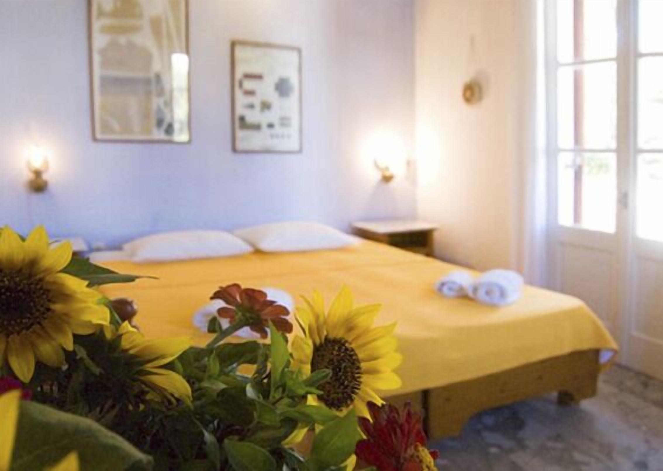 A bedroom with a bed, pillows, a nightstand, and a window.
