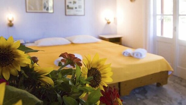Un dormitorio con cama, almohadas, mesita de noche y ventana.