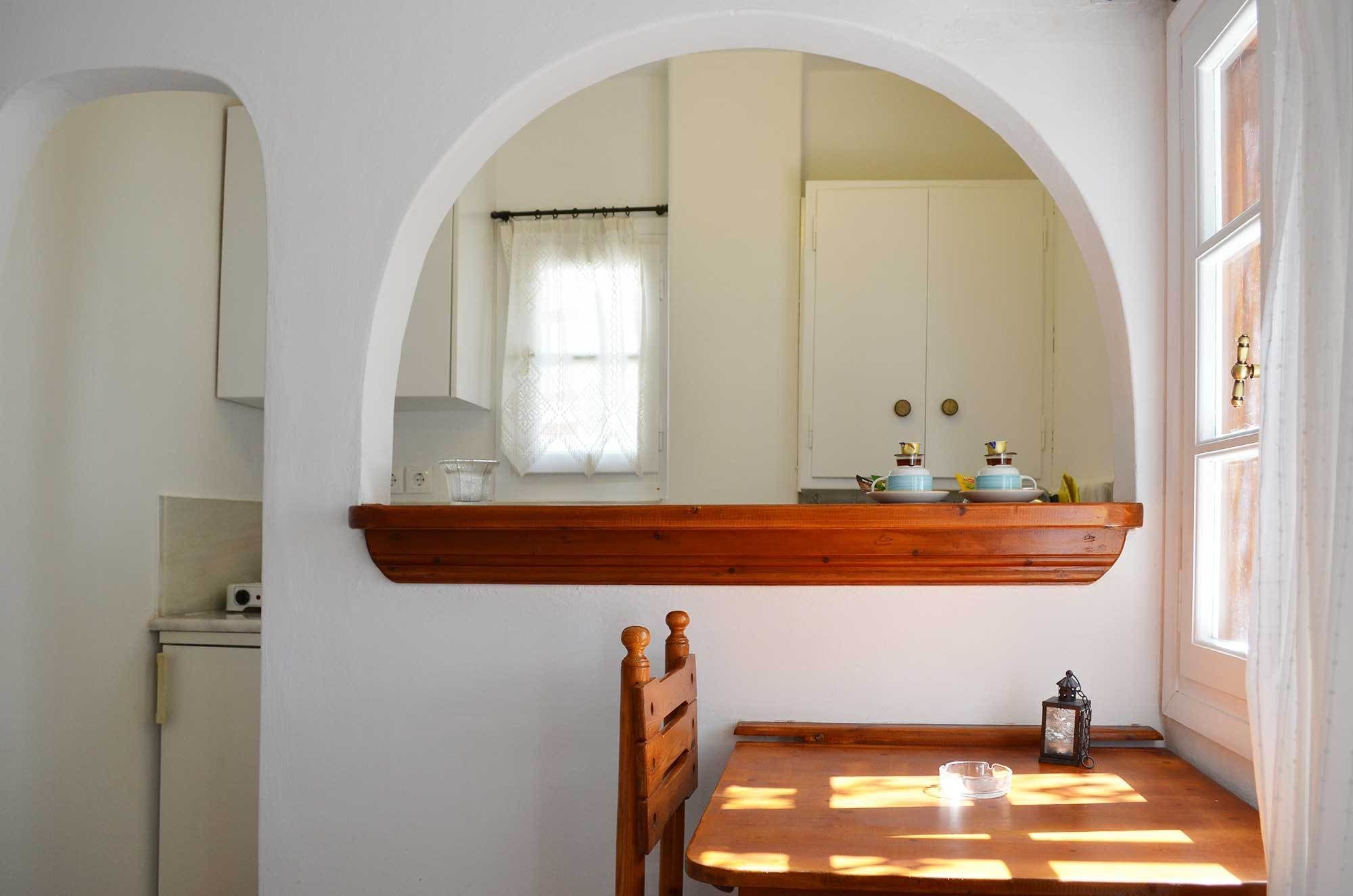 Une pièce comprenant une table en bois, une chaise, un petit meuble et un miroir doté d’un cadre en arc de cercle.