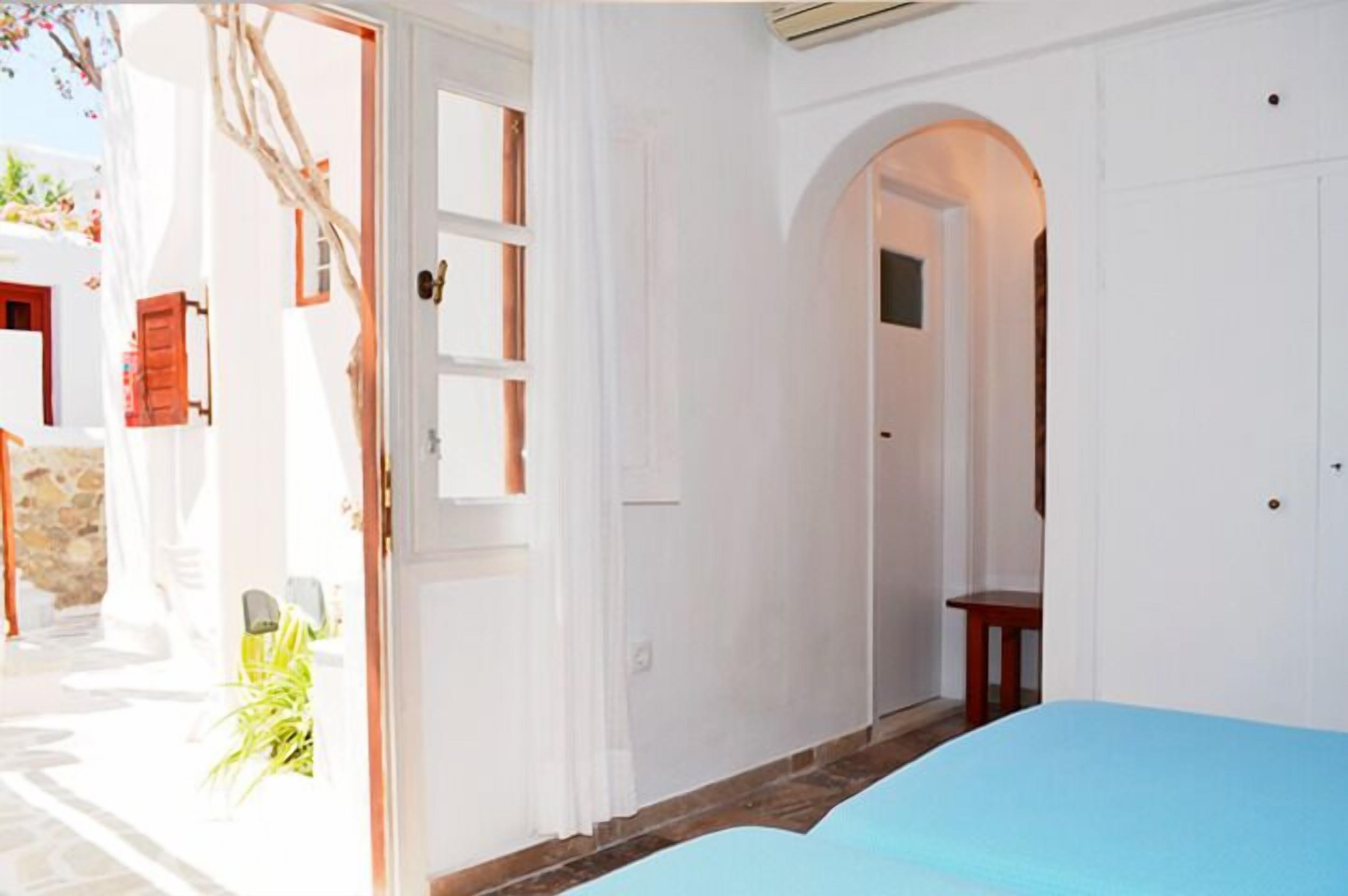 A room with a bed, an arched doorway, and a view of the outside.