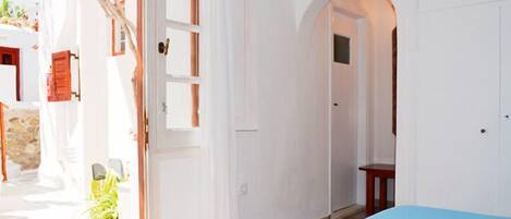 A room with a bed, an arched doorway, and a view of the outside.