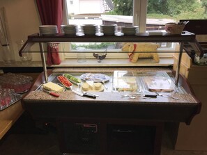 A buffet setup with plates, bowls, and food items on a counter. - Landgasthof Germania (Ruedesheim am Rhein)