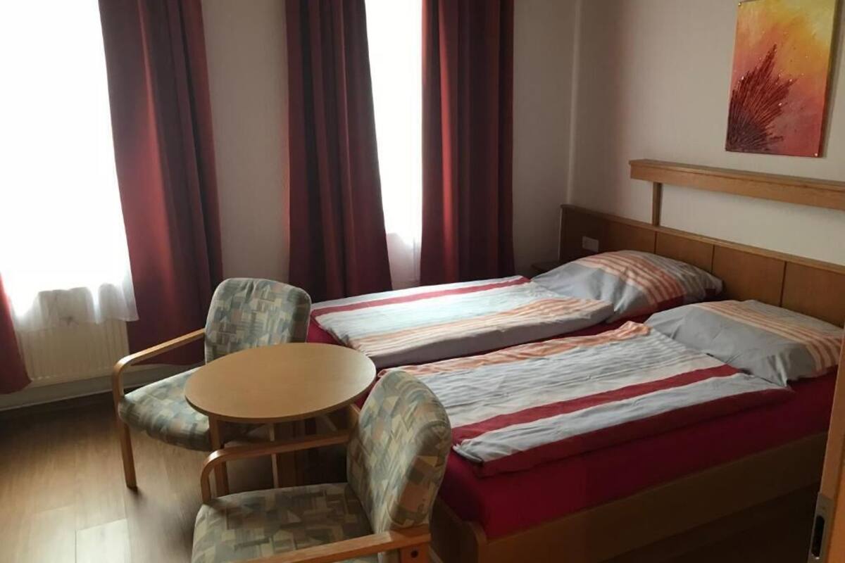A room with two beds, a round table, and two chairs.