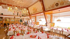 A restaurant with multiple dining tables set for service, a chandelier, and decorative wall art. - Landgasthof Germania (Ruedesheim am Rhein)